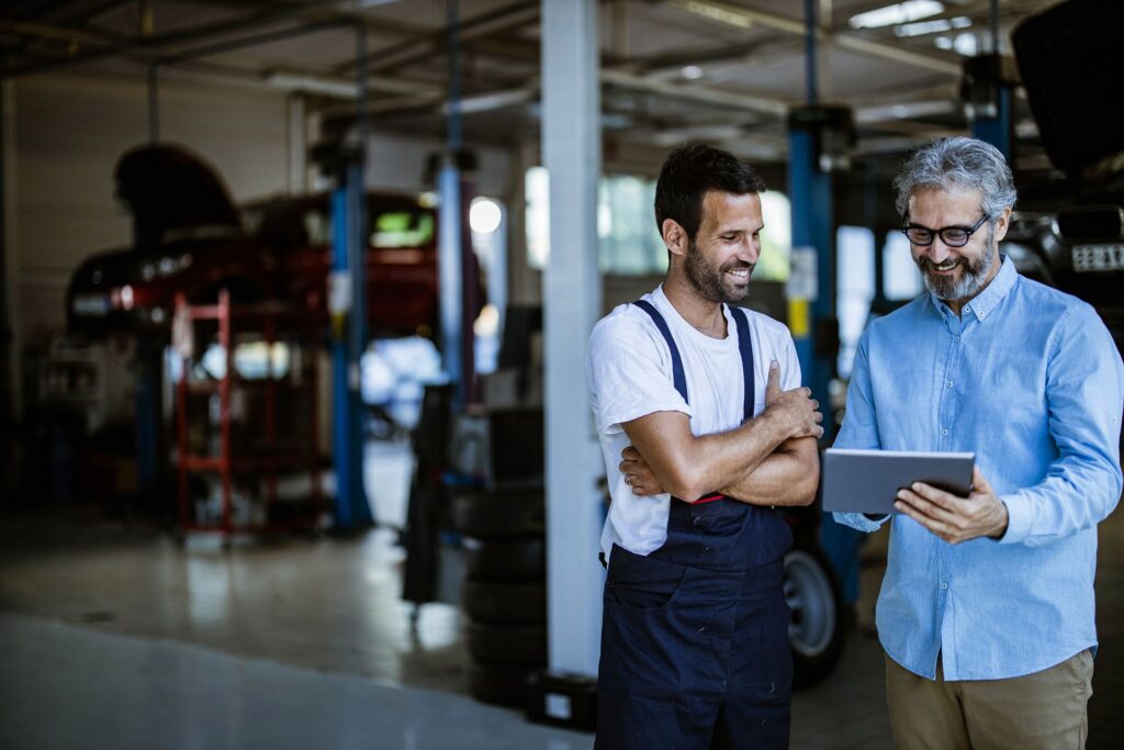 Mechanic and business owner viewing garage management software on tablet device