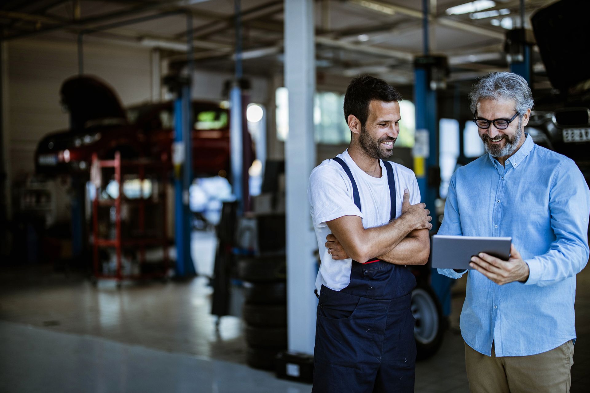 Mechanic and business owner viewing garage management software on tablet device